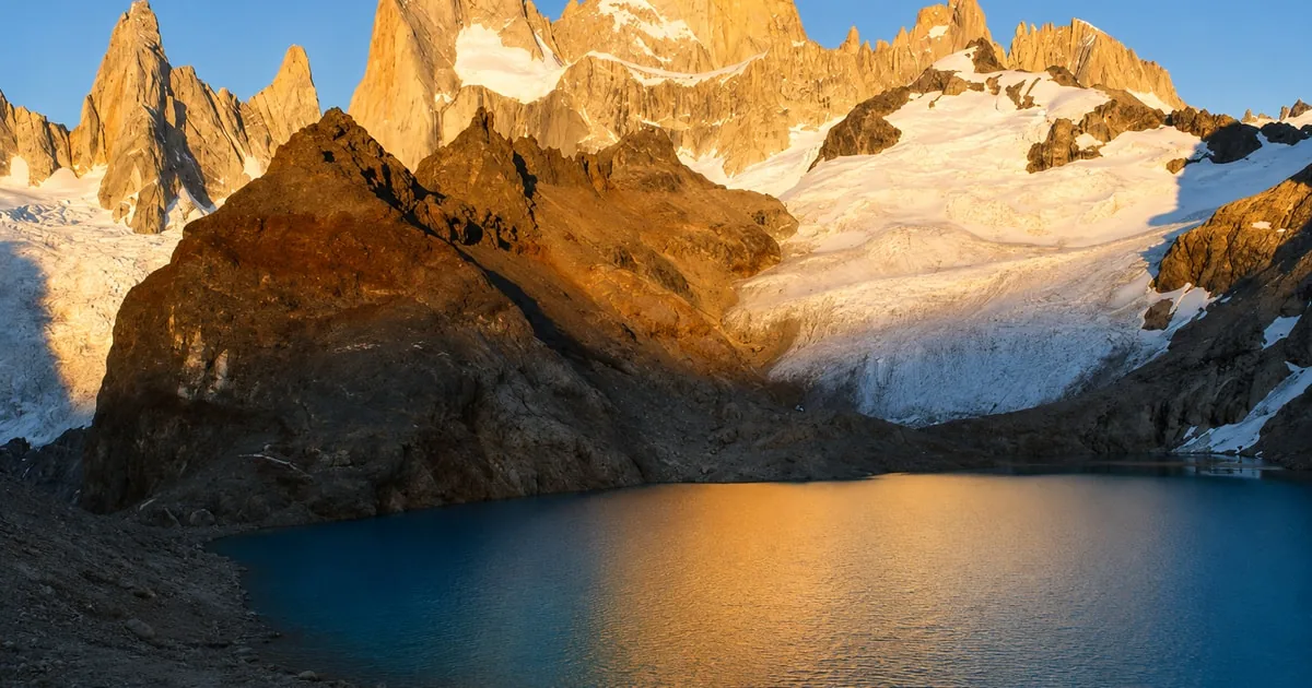 The Fitz Roy granite spires glowing orange above a dark lagoon, Laguna de los Tres