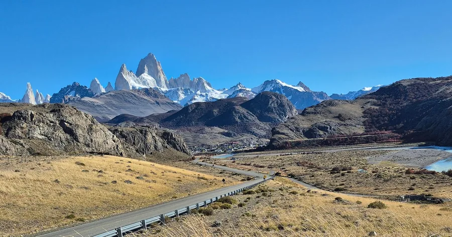 Mount Fitz Roy and its snowy neighbours rising above the brown Patagonian steppe under a blue sky